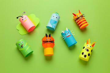 Homemade figures of animals from rolls of paper on green background. Creative kids toys, zero waste. Copy space for text.
