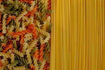 Background with dry pasta - spaghetti and multicolored spiral pasta