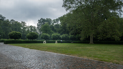 Herrenhaus Vorgarten mit Skulpturen. Ein Man mit Regenschirm beim schlechtem Wetter.