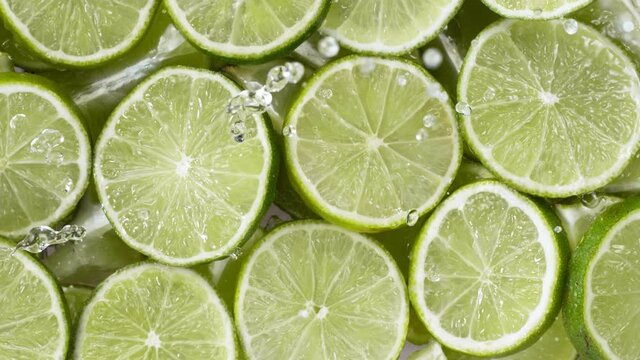 Super slow motion of lime slices with splashing water, top view. Filmed on high speed cinema camera, 1000 fps.
