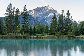 Banff National Park beautiful scenery. Cascade Mountain and pine trees reflected on turquoise color Bow River in summer time. Town of Banff, Canadian Rockies, Alberta, Canada.