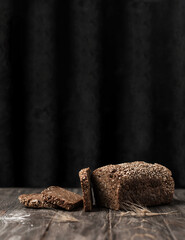 Sliced rye bread on a wooden dark background with copy space. Whole grain rye bread with sesame seeds and seeds.