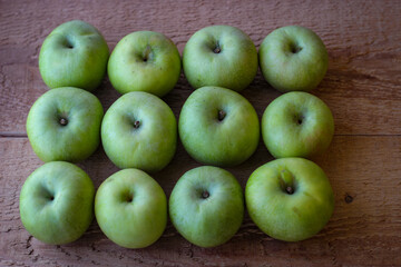 Green apples stand on a wooden surface