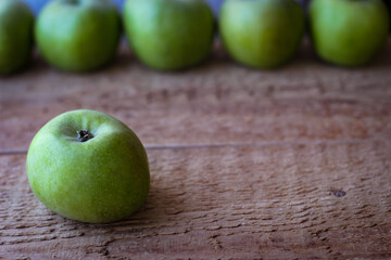 Green apples stand on a wooden surface
