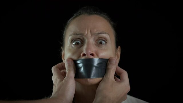 The concept of restricting freedom of speech. The woman's mouth is sealed with adhesive tape.