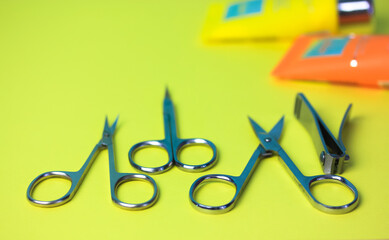 Set of sharp steel manicure scissors and spikes isolated on the yellow green table surface. Professional tools for manicure and pedicure. Beauty Scope. Open scissors on the table. Top view. Flatly.