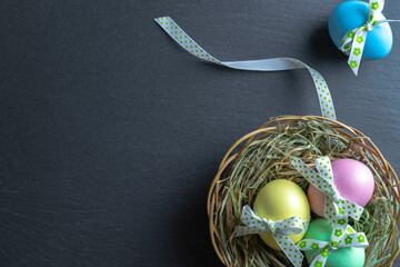 Easter background blue. Colourful egg with tape ribbon on dark rough stone background in Happy Easter decoration. Flat lay, top view.