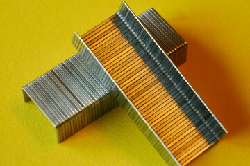 close up of metal staples on yellow paper