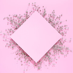 Silver dry flowers with pink paper card note on pink background. Creative flat lay concept with negative space.