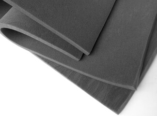 curved folds of two gray industrial sponge foam sheets on a white background.  rubber foam material...