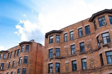 Fototapeta na wymiar Old brick apartment buildings against bright blue sky with clouds, horizontal aspect