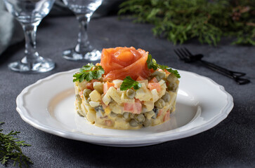 Traditional Russian salad Olivier with salted salmon on dark background. Festive presentation.