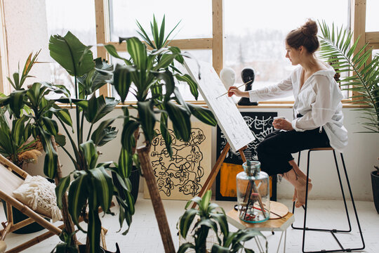 Side view of female artist painting on canvas