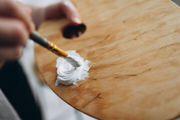 Female using brush for mixing white color on palette