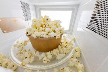 Spilled popcorn in the microwave. Salty snack prepared in the kitchen appliance.
