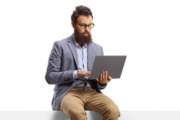 Bearded man with on a laptop sitting on a panel