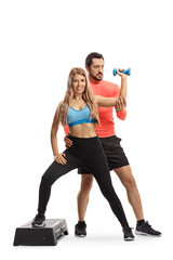 Male trainer showing a woman an exercise with a dumbbell on a step platform