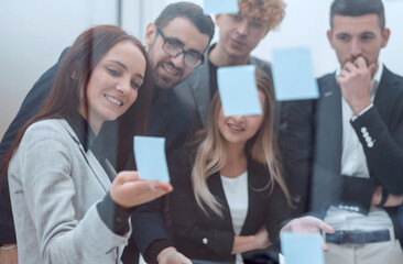 employees discussing sticky notes on the glass