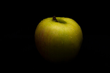 green apple sprinkled with water on a black background
