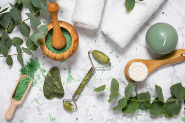 Natural wellness and anti aging skin care with beauty jade roller, gua sha , bath salt and eucalyptus branch on marble background. Spa, face massage, relaxation concept. Top view, flat lay © Julia Lavrinenko