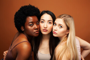 Obraz premium young pretty asian, caucasian, afro woman posing cheerful together on brown background, lifestyle diverse nationality people concept
