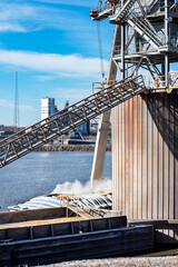 Grain elevator terminal barge spout loading grain corn into dry bulk cargo barge on Mississippi River during harvest season. Agriculture, agricultural, exporting crops, food, maritime, marine,  © Jon