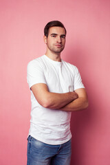 young caucasian guy in white t-shirt posing cheerful on pink background, lifestyle people concept