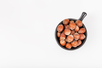 Fresh shelled hazelnuts in a black bowl isolated on white background.