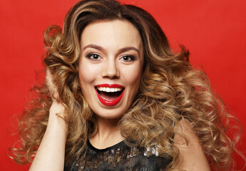 lifestyle, party and people concept - Gorgeous blonde woman in an evening dress flirty and playful on a red background