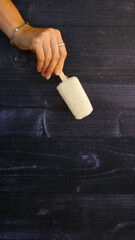 Paleta de helado de vainilla sostenida por una mano de mujer