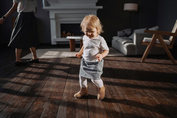 Dancing at home to the music. Cute little blonde girl. The child smiles in a cheerful mood. He plays his own games. Clothing stylish children's dress and shoes.