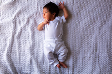 beautiful newborn hispanic baby on a white sheet, calm and relaxed