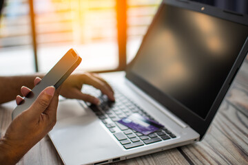 Men use smartphones to shop online. Businessmen transfer money via the Internet. A man's hand holds a smartphone to payment. Business people use laptops on a desk. Selective focus. Blurred background.
