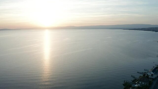 Aerial reveal of houses at the shore of beautiful lake at sunset