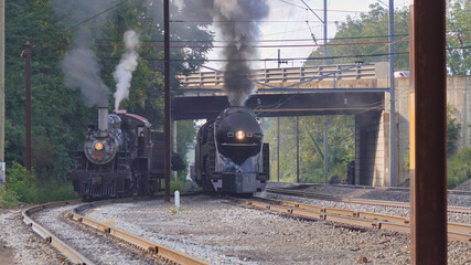 View of 2 Locomotives Spanning Over 50 Years Passing Each Other Under a Bridge.