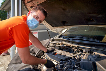 Smart male mechanic try to repair the engine of car in automotive garage
