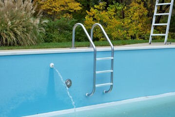 backyard swimming pool with pool slide and ladder emptied out shutting down for winter © PictureThisImages