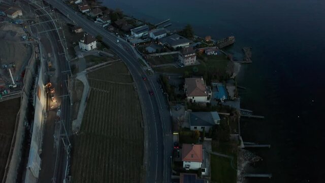 Aerial of highway at the edge of small town, tilting up to beautiful lake at dusk