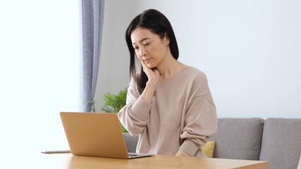 パソコンを見て悩むミセス女性