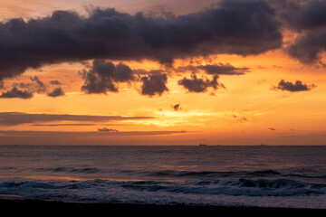 Intense sunrise at the beach in Chiba Japan, this beach is famous for surfing and is close to a place where surfing competitions in Japan are held. The colors in the sky are orange and yellow.