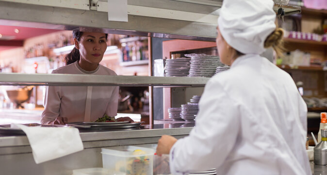 smiling female waiter geting order from chef in restaurante