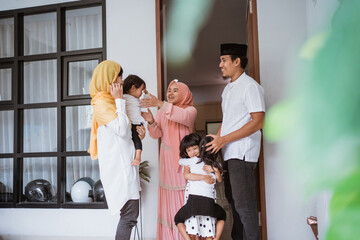 excited asian muslim family visiting friend during eid fitri mubarak at home