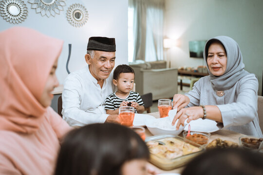 Breaking The Fast. Muslim Asian With Hijab Having Iftar Dinner Together At Home Sitting On Dining Table