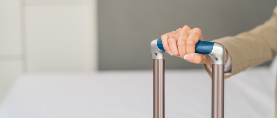 close up of woman hand holding suitcase handle in hotel room