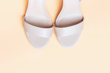 Female sandals on beige background close-up top view, copy space.