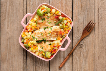 Grilled homemade chicken with various delicious vegetables on a light wooden background. Top view.