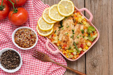 Baked homemade chicken from the oven with vegetables and lemon. Tableware. Top view.