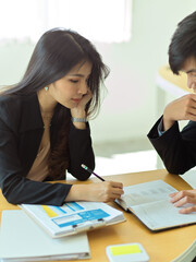Female office worker discussing with her coworker with business document in office room