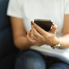Female office worker using smartphone in her hands while relaxing in cafe