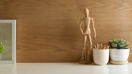 Close up view of the table with copy space, wooden figure, pencils, plant pot and frame